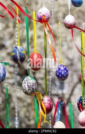 Painted eggs hang from the branches of the Easter tree. The focus is on a yellow egg painted by children by hand. High quality photo Stock Photo