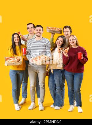 Group of friends with tasty pizza and drinks on yellow background Stock Photo