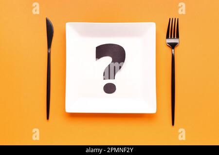 Plate with question mark and cutlery on orange background Stock Photo