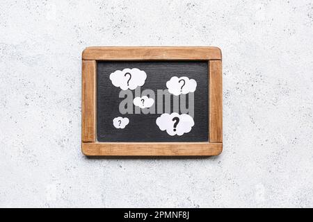 Chalkboard with clouds and question marks on white background Stock Photo
