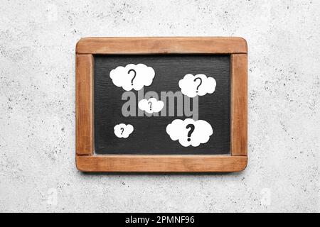 Chalkboard with clouds and question marks on white background Stock Photo