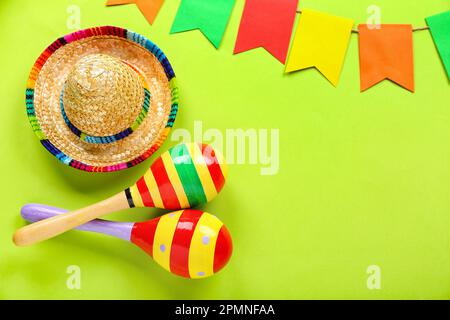 Frame made of Mexican maracas with sombrero hat and flags on green background Stock Photo