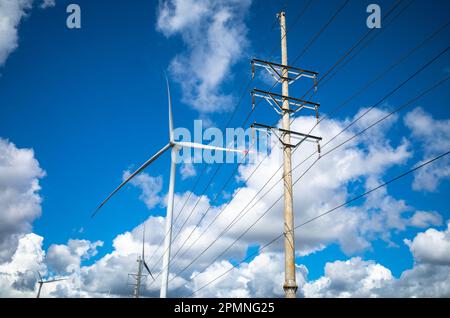 Giant wind turbines next to electricity transmission lines on the plateau in the Central Highlands of Vietnam in Gia Lai Province. Stock Photo