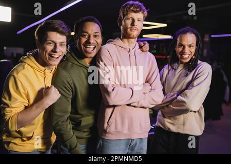 Cheerful interracial friends looking at camera in gaming club,stock image Stock Photo