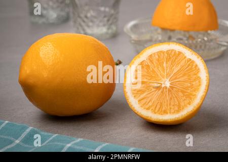 Whole and halved fresh Meyer lemon close up in front of a lemon press Stock Photo