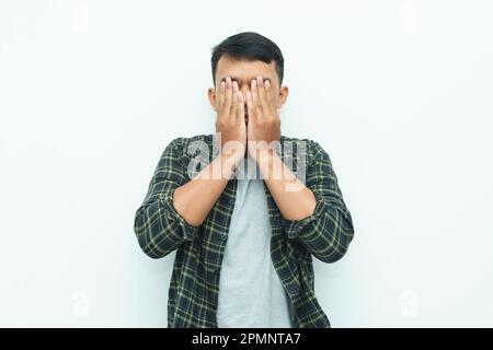 Young Asian man covering his face using hand palms Stock Photo