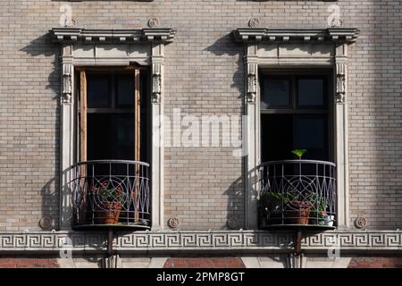 Decorative balconies on a residential building. The wrapped wrought iron railings with red geraniums makes for a lovely urban setting Stock Photo
