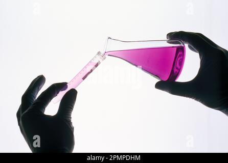 Studio shot of a gloved hand chemical being poured into a glass tube;  New York City, New York, United States of America Stock Photo