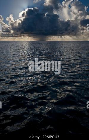 Dark storm cloud drops rain over the ocean; Seychelles Stock Photo