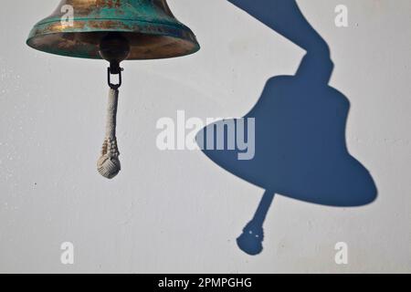 Bell casts a shadow on a white background; Mayotte, M'Bouzi Island, France Stock Photo