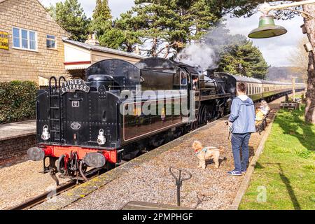 Passengers & dog awaiting the arrival of a steam train pulled by Braveheart, British Railways Standard class 4 4-6-0 No. 75014 at Gotherington Station Stock Photo