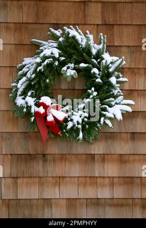 Snow-dusted evergreen wreath on a wood facade; Lake Placid, New York, United States of America Stock Photo