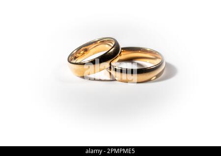 Two shining gold wedding rings isolated on white background, symbolizing the bond of marriage and everlasting love Stock Photo