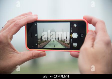 Using a cell phone to take a photo of the Taj Mahal on a foggy day; Agra, India Stock Photo