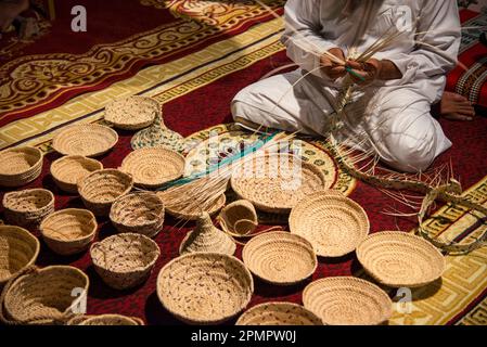 Basket weaver selling his wares while working on a new piece; Muscat, Oman Stock Photo