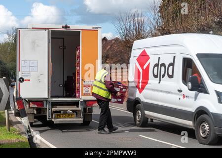 A Sainsbury's delivery van parked with the driver delivering groceries to a home, whilst a DPD van drives past, England, UK Stock Photo
