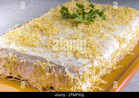 Chilled salty chicken pie, typical Brazilian dish. In a golden shape, gray wooden background and coriander detail on the pie. Perspective view. Stock Photo