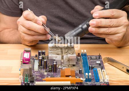 Cleaning the motherboard. Dirt on the processor. Tweezer for cleaning of dirt, cleaning with a vacuum cleaner Stock Photo