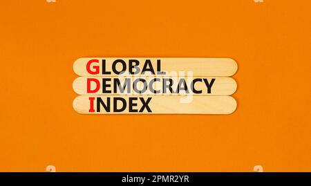 GDI global democracy index symbol. Concept words GDI global democracy index on wooden stick on a beautiful orange table orange background. Business an Stock Photo