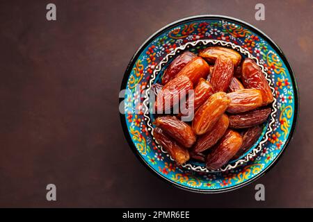 Dried dates in bowl on a dark background. Bowl of pitted dates. Food for Ramadan. Top view. Copy space Stock Photo