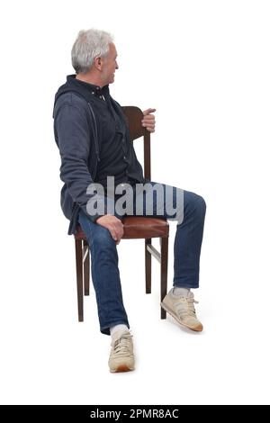 man sitting on a chair from the front who turns and looks into the background on white background Stock Photo