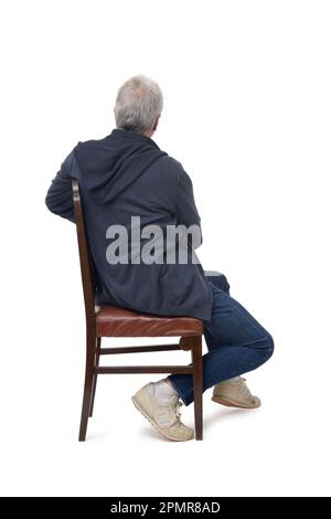 man sitting on a chair from the side who turns and looks into the background on white background Stock Photo