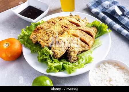 Fried "peroa" fish, lettuce salad, tomato, lemon, rice, beans and passion fruit juice. Traditional Brazilian beach food known as: "Peixe Frito Capixab Stock Photo