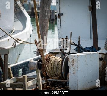 Old, well used nautical rope and winch on the deck of a moored commercial fishing boat. Stock Photo