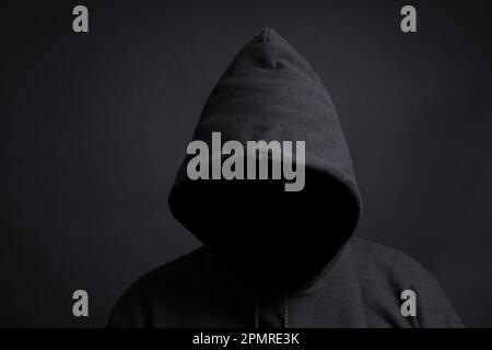 faceless person wearing black hoodie hiding face in shadow Stock Photo