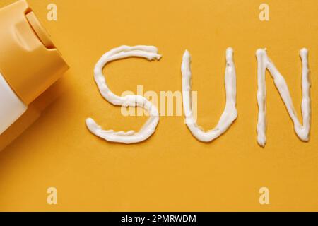 Bottle With Sunscreen And Word Sun Made Of Cream On Yellow Background 