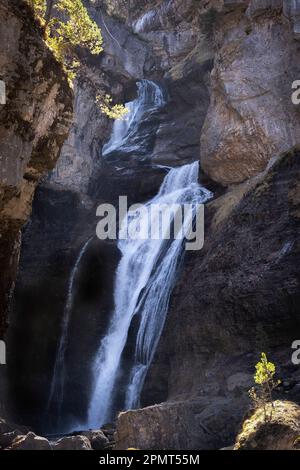 The cave waterfall in the heart of the National Park of Ordesa and Monte Perdido, set in a rocky canyon, branches and small tree with autumn colored l Stock Photo