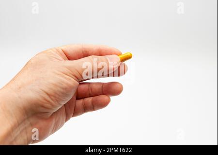 Man hand holding Turmeric supplement capsule isolated on white background with copy space. Stock Photo
