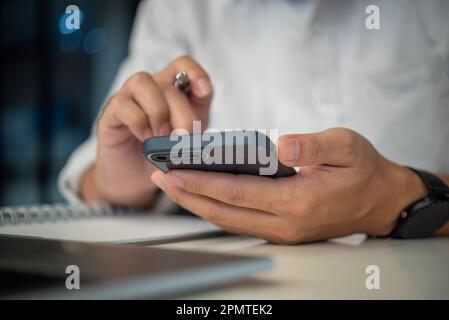 man using mobile smart phone and working on laptop computer.education and technology concept, student working, Freelance. Stock Photo