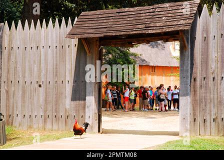 An opening in the stockade fence offers a peak into the Jamestown Settlement, a museum and recreation of the first English establishment in America Stock Photo