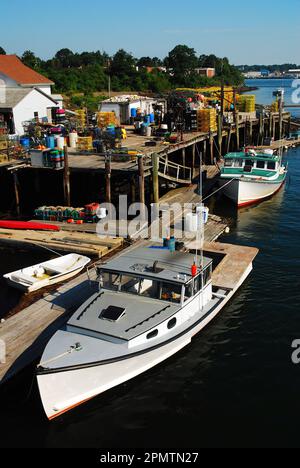 Boats are docked at a small commercial fishing harbor, with lobster traps on the pier, near the coastal town of Portsmouth, New Hampshire Stock Photo
