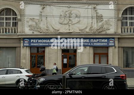 Voronezh, Russia. 12th Apr, 2023. Branch of the bourgeois party in power 'United Russia' under the old Soviet bas-relief on Revolution Avenue in Voronezh. By mid-April, spring warmth came to Voronezh. In a city with a million inhabitants, the last snow has melted, and people have changed their winter clothes to lighter ones. Credit: SOPA Images Limited/Alamy Live News Stock Photo