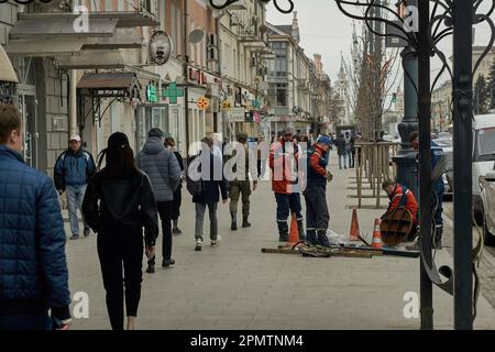 Voronezh, Russia. 12th Apr, 2023. Repair of the path and passers-by inhabitants on Revolution Avenue in Voronezh. By mid-April, spring warmth came to Voronezh. In a city with a million inhabitants, the last snow has melted, and people have changed their winter clothes to lighter ones. Credit: SOPA Images Limited/Alamy Live News Stock Photo