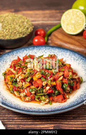 Gavurdagi salad. Walnut salad on wood background. Healthy salad prepared with tomatoes, peppers, cucumbers, onions, pomegranate syrup, olive oil and w Stock Photo