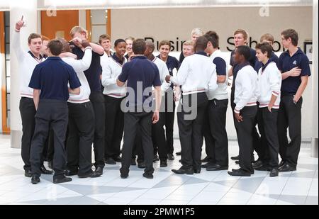 A group of students wearing matching shirts and black slacks in a classroom setting Stock Photo