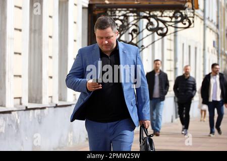 Man in business suit using smartphone while walking down the street. Using mobile phone in spring city Stock Photo