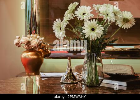 White gerberas in a vase near the mirror stand on the table. Stock Photo