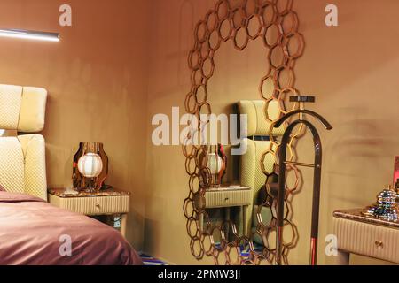 The mirror in the bedroom hangs on the wall. The edging is decorated in the form of golden honeycombs Stock Photo