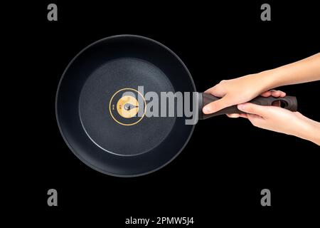 Top view of female hands holding a new round frying pan isolated on black background. Stock Photo
