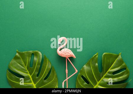 Summer beach party concept. Pink flamingo and tropical leaf monstera on green background. Flat lay, copy space. Stock Photo