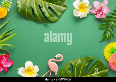 Exotic jungle summer frame. Summer beach party concept. Pink flamingo, tropical leaf monstera and orchid flowers on green background. Flat lay, copy s Stock Photo