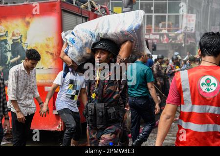 A Border Guard Bangladesh (BGB) personnel helps business owners to bring out their goods after a horrendous fire guts shops at the clothing market in Dhaka. A large fire has gutted thousands of shops at a popular clothing market in the Bangladeshi capital, Dhaka, with shop owners devastated by the loss weeks before Eid, the Muslim festival marking the end of Ramadan. Hundreds of firefighters and army personnel battled the inferno as it tore through the clothing market, turning it into a pile of ashes. Several people have been injured but no deaths have been reported so far. Authorities were st Stock Photo