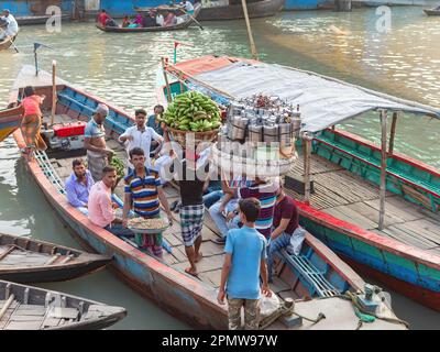 Men carrying bunches of green bananas and other products to local ferries at Wise Ghat Boat Station on Buriganga River in Dhaka, the capital of Bangla Stock Photo