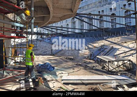 Construction site with workers in bright vests busy with construction. Reinforced concrete structures and engineering communications Stock Photo
