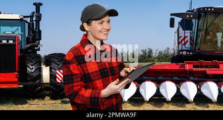 Farmer with digital tablet on a background of combine harvester and tractor. Smart farming concept. High quality photo Stock Photo