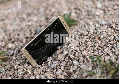 broken phone on stone paved sidewalk outdoors. Lost on walk smartphone with broken screen Stock Photo